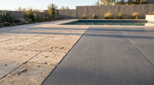 French pattern ivory travertine pavers meeting large-format gray porcelain pavers along a diagonal seam on a sunlit pool deck